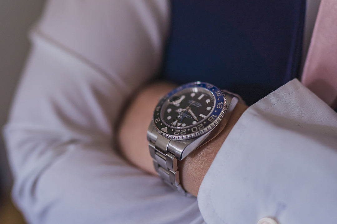 Luxury Rolex GMT Master II "Batman" on a wrist with crossed arms.